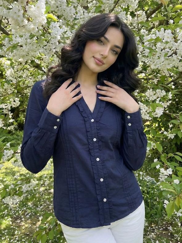 Woman wearing a navy blue shirt with white buttons.